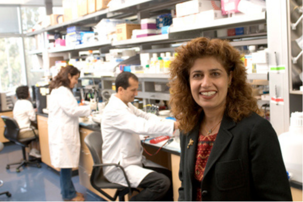 Dr. Sarwal smiling in a lab with researchers behind her