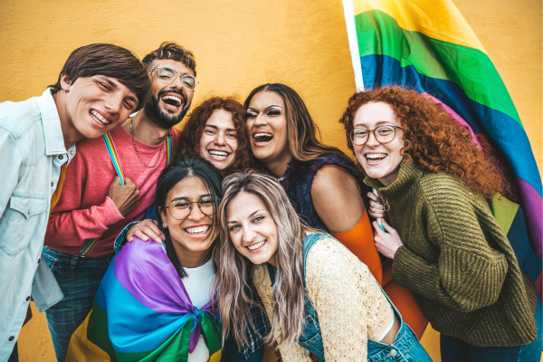 Group of happy LGBTQIA+ individuals hugging and smiling