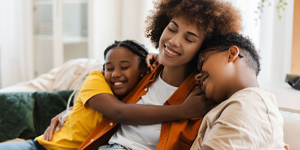 Family sitting and cuddling on the couch, looking happy and relieved