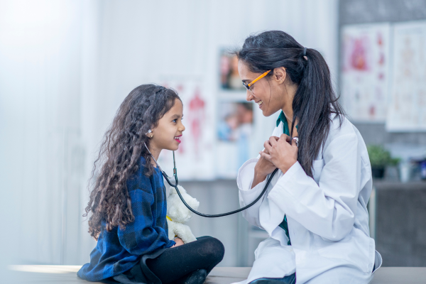 Child using stethoscope on doctor
