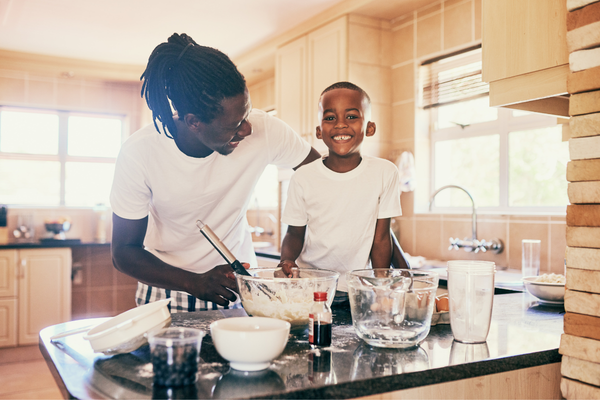Un padre y su hijo preparan el desayuno juntos y felices