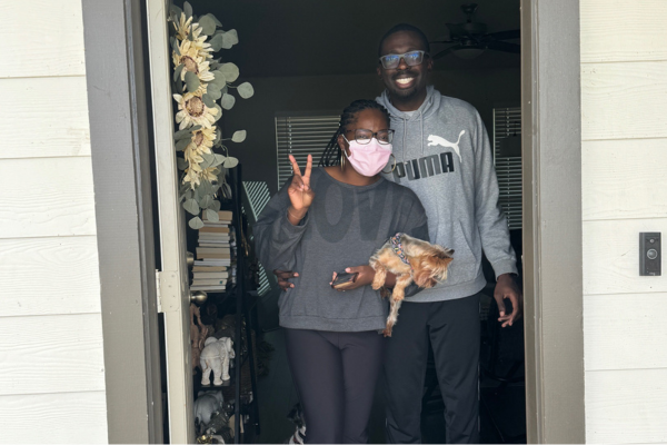 Kamri giving peace sign and holding dog next to Latonna