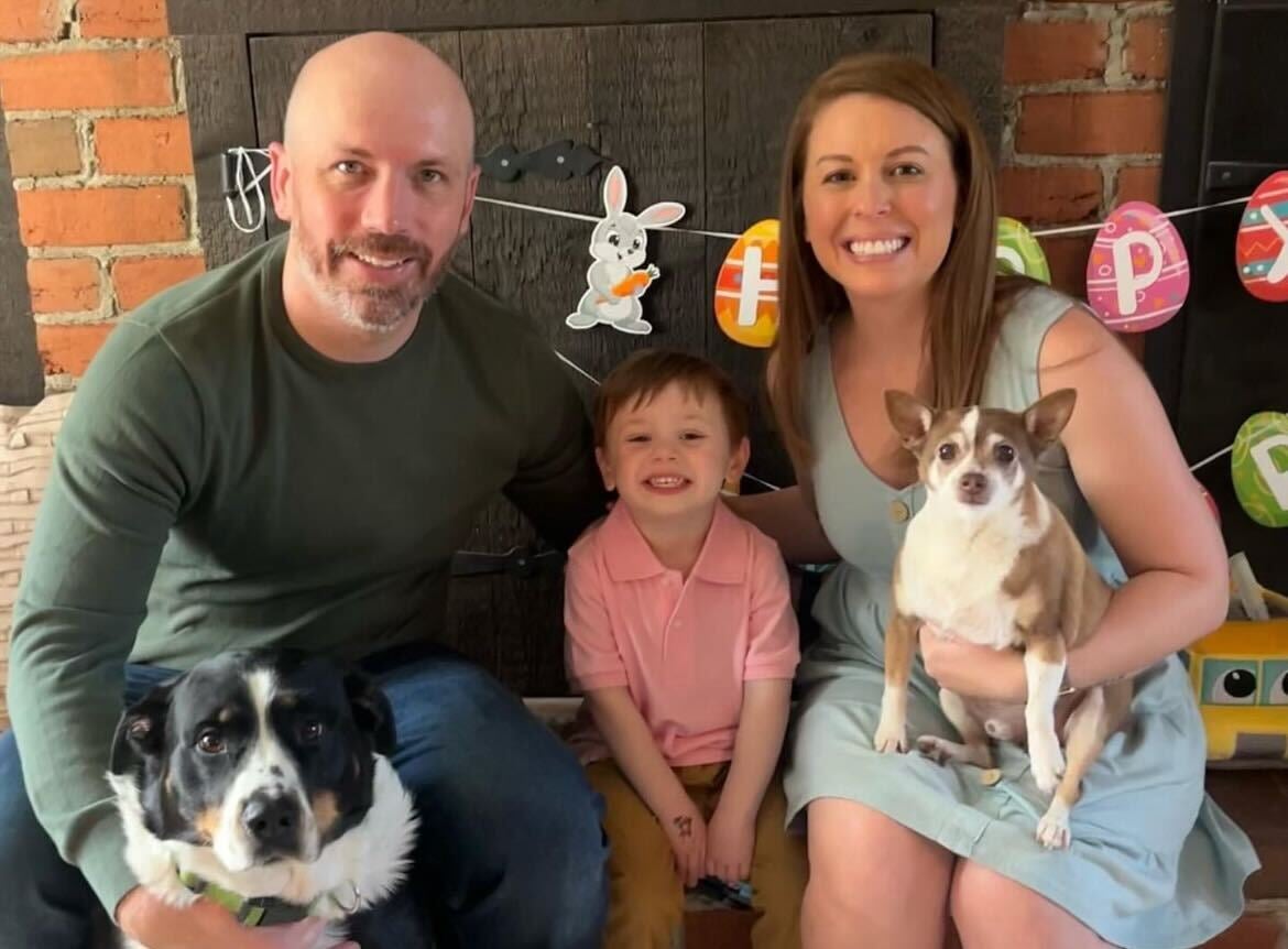 Lauren, her husband, their son, and their two dogs sitting down and smiling