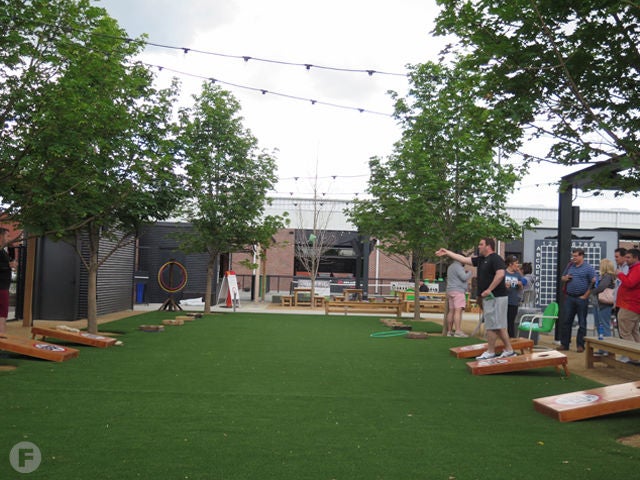 a group of people playing corn hole on the patio of Chicken N Pickle restaurant