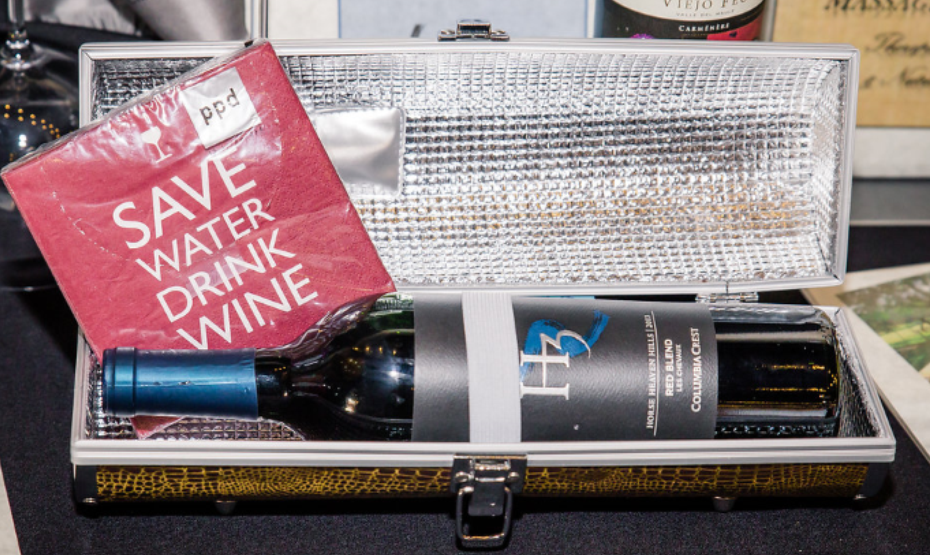 a bottle of wine in an opened case. There is a napkin that says Save Water; Drink Wine draped over the case
