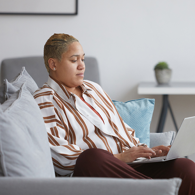 Woman sitting on her couch looking at her laptop