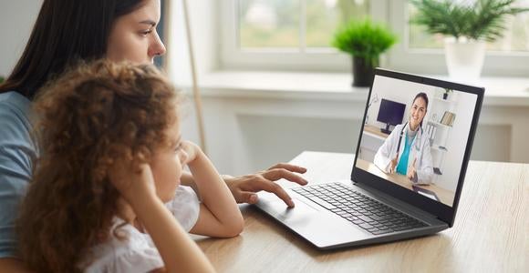 A mother and child watching a doctor on a computer