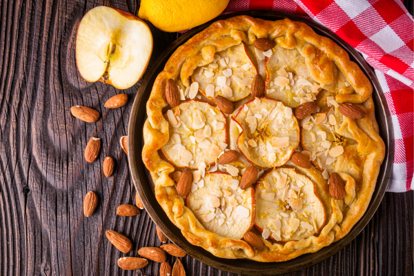 Apple almond galette pie on a table with almonds and apple half nearby