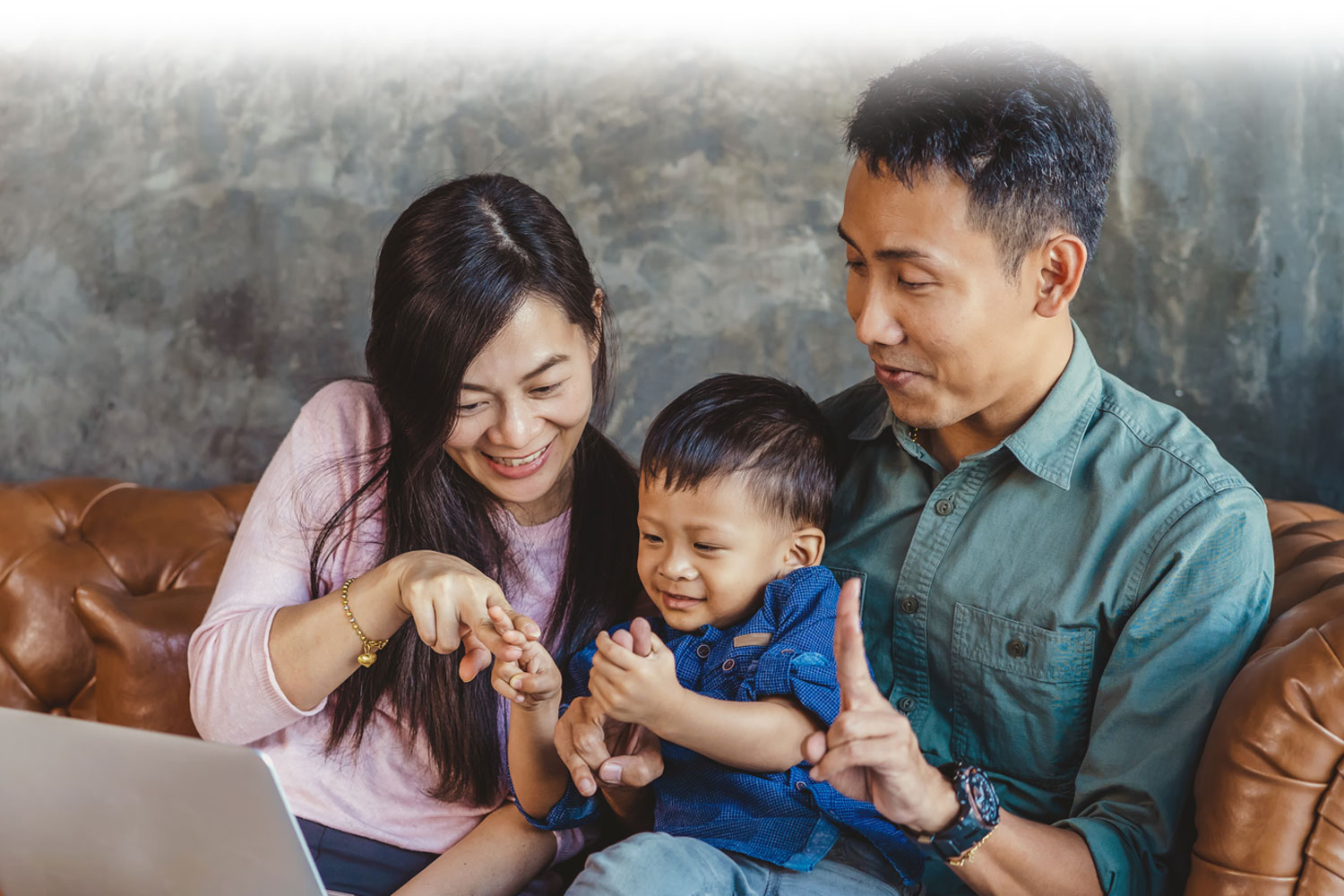 Family with small child enthusiastically looking at information on a laptop