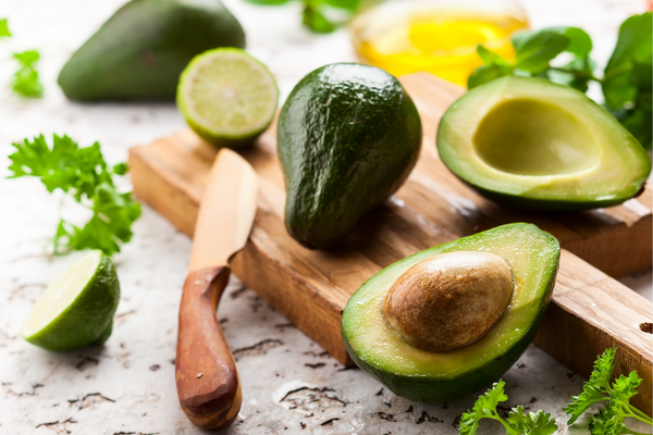 Avocados on a cutting board next to a knife