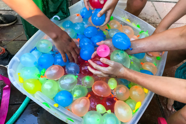Hands reaching into a bucket of water balloons