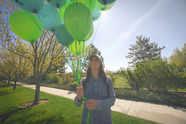 Person smiling and holding a bunch of balloons