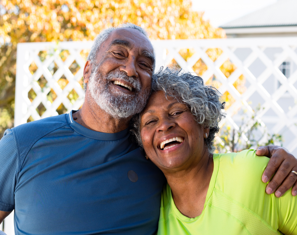 An older couple smiling and embracing while facing the camera