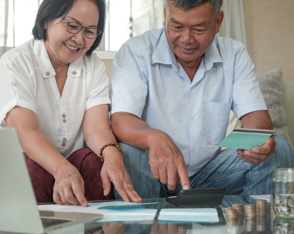 two older people working together on forms while sitting on the couch