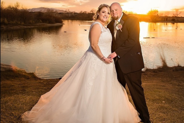Christina and Michael posing in wedding attire in front of sunset