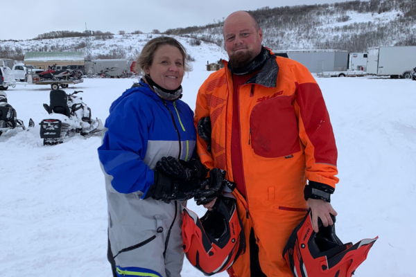 Christina and Michael in snow suits, holding helmet for snowmobiling