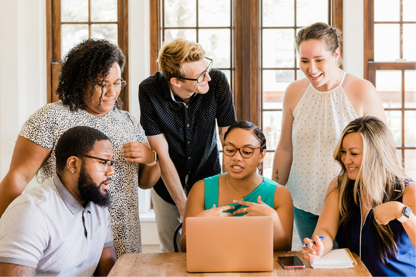 Large group of professionals gathered around computer to learn