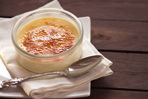 Ramekin of creme brulee with crispy top sitting on napkin