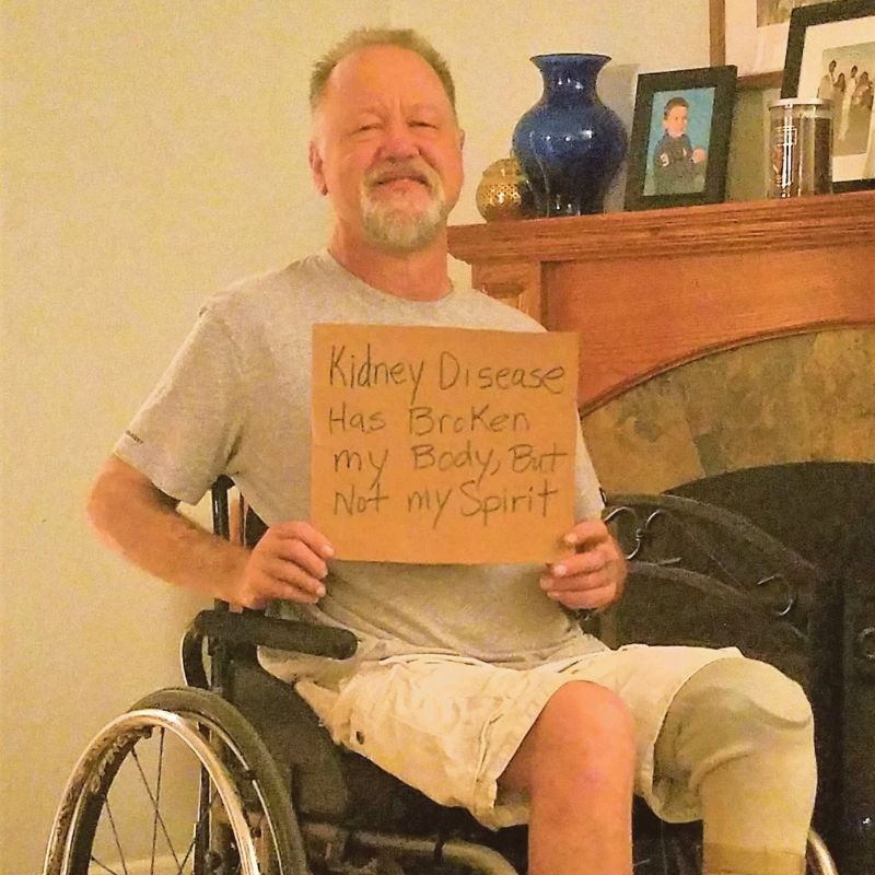 Derek Forgang holding sign that reads "Kidney disease may have broken my body but not my spirit."