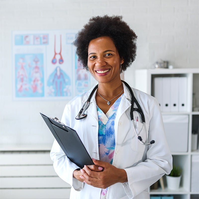 Doctor standing in her office with a kidney anatomy chart on the wall