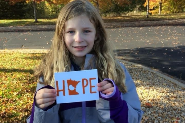 Emma Slater smiling holding a sign that says hope.