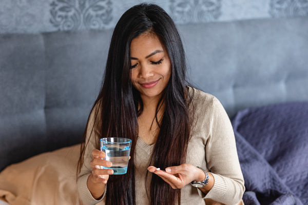 Person on bed smiling at pills in their hand.