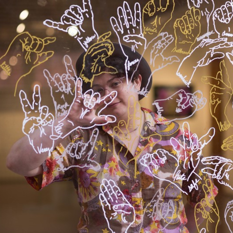 Jess captured with "Can You Lend A Hand?," their interactive ASL-themed temporary mural installation at New City Arts Initiative February, 2022. Photo Credit: Kori Price