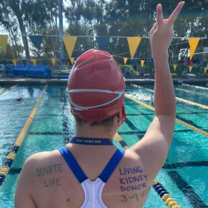 June in swimsuit with "Living Kidney Donor 3/9/05" and "Donate Life" written on her back.