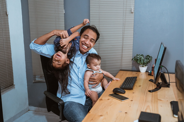 Parent on the computer with giggling children on them.