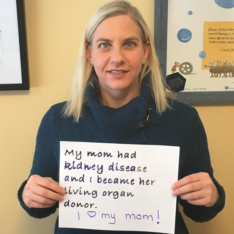 Person holding sign "My mom had kidney disease and I became her living organ donor."