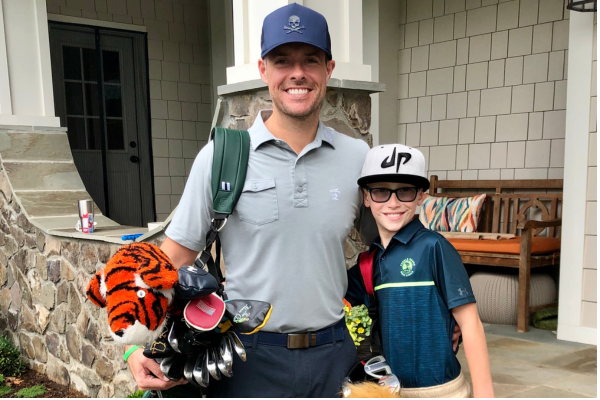 Logan with his dad holding golf equipment