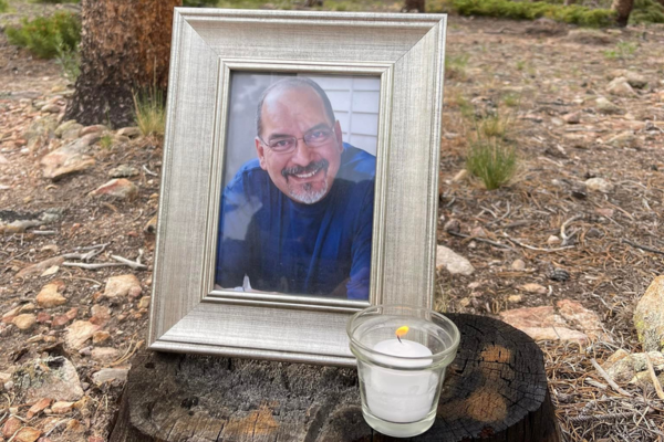 Anthony Lovato memorial photo on a log with candle near by