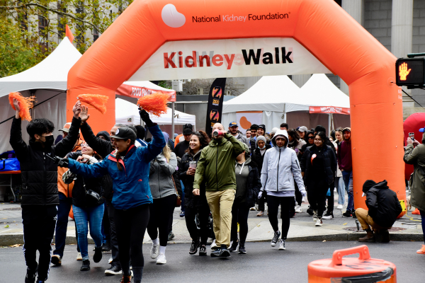 Gran grupo de personas entusiastas con un cartel de Kidney Walk