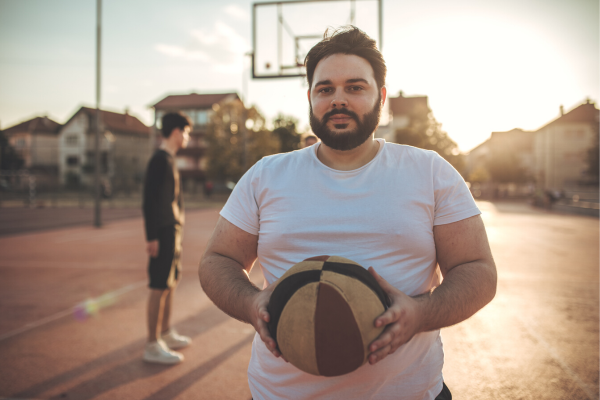 Person holding basketball on outdoor court
