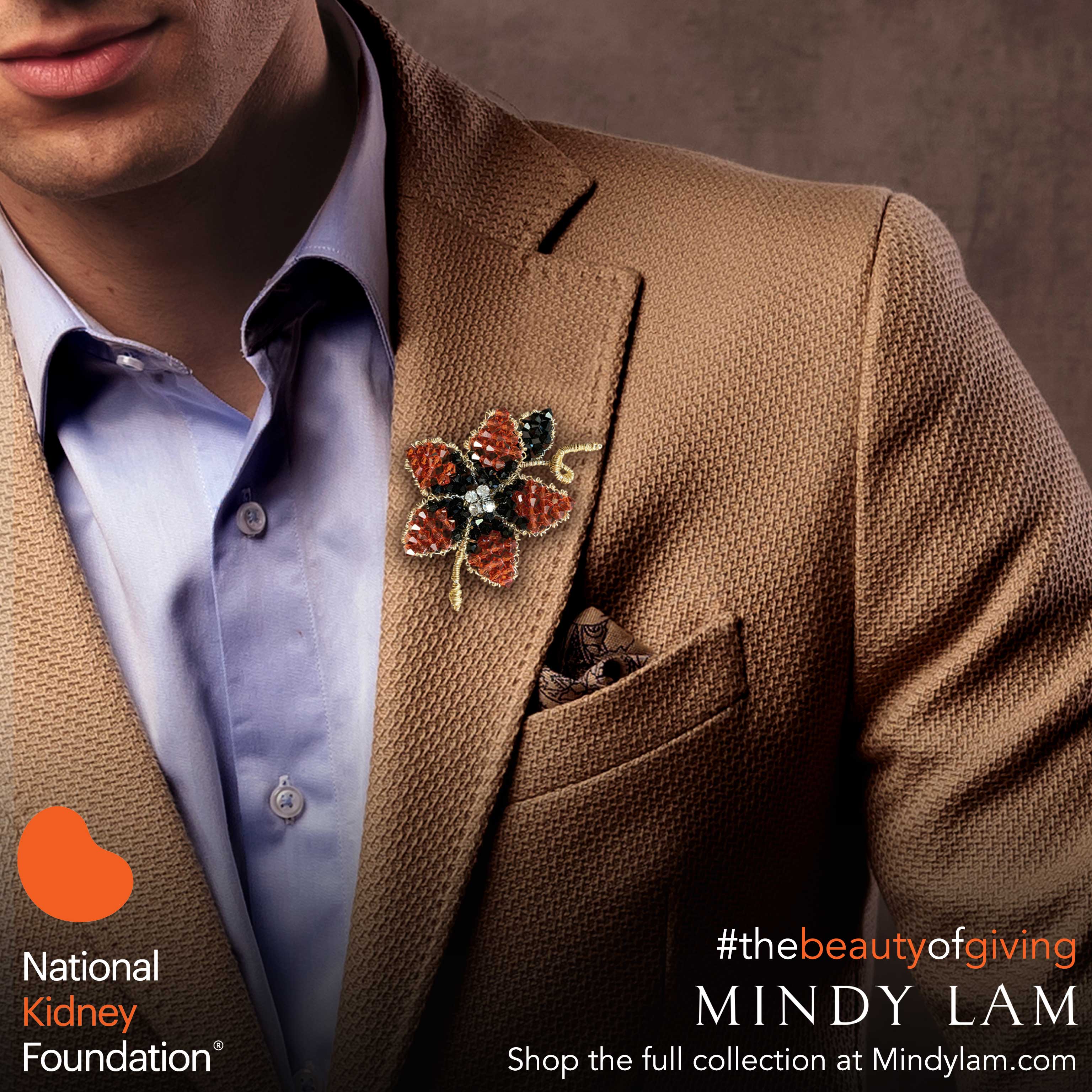 a closeup of the lapel of a brown suit showing a orange lapel pin designed by Mindy Lam