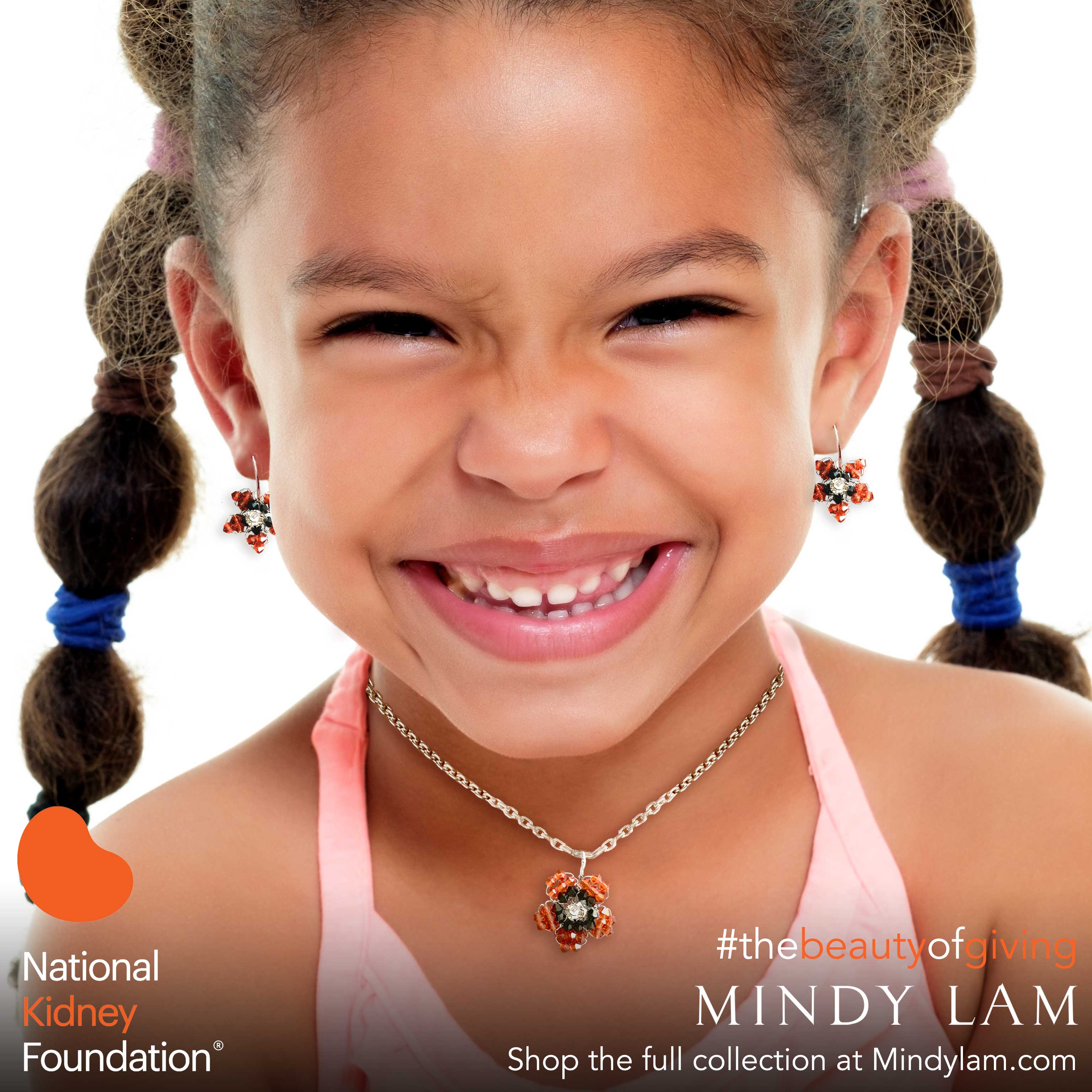 a young African American girl with a huge smile wearing a pair of orange earrings and an orange necklace designed by Mindy Lam