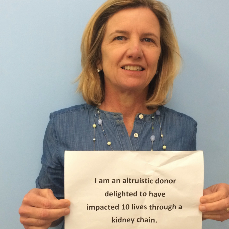 Person holding sign "I am an altruistic donor delighted to have impacted 10 lives through a kidney chain"