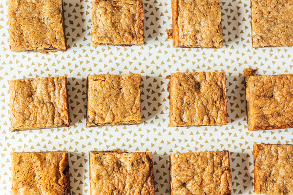 Rows of square pineapple bar cookies on a table cloth.