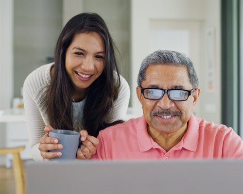 daughter encouraging her father while he looks at a laptop