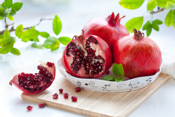 Pomegranates cut open on clean cutting board.