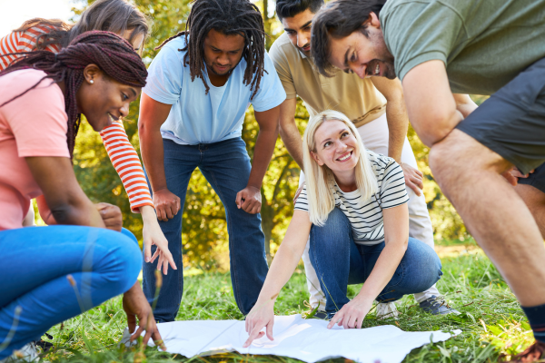 Group of people excitedly kneeling over a map and talking 