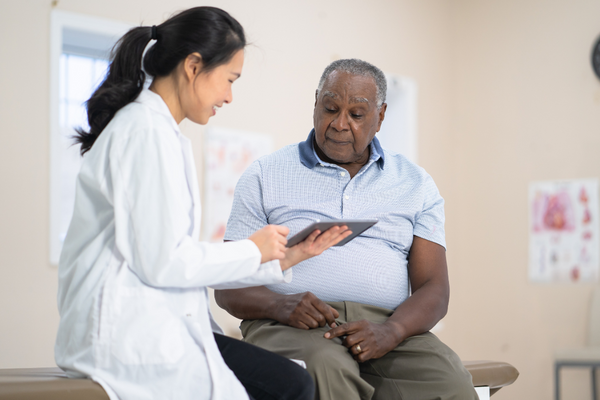  Happy doctor showing interested patient information on tablet.