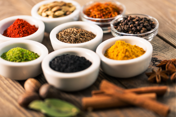 Anise, bay leaf, cinnamon, caraway seed, curry powder, pepper, and chili powder in small bowls. 