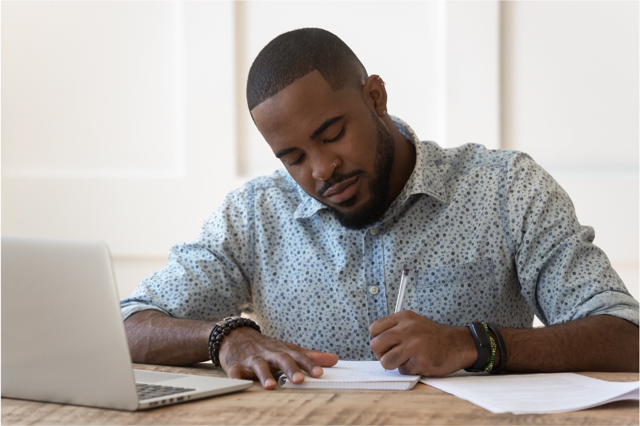 Man sitting at desk taking notes in front of computer