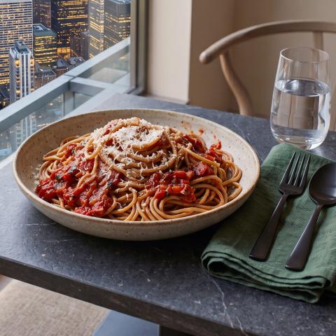 Whole wheat pasta with marinara sauce and parmesan in a bowl on an elegant table