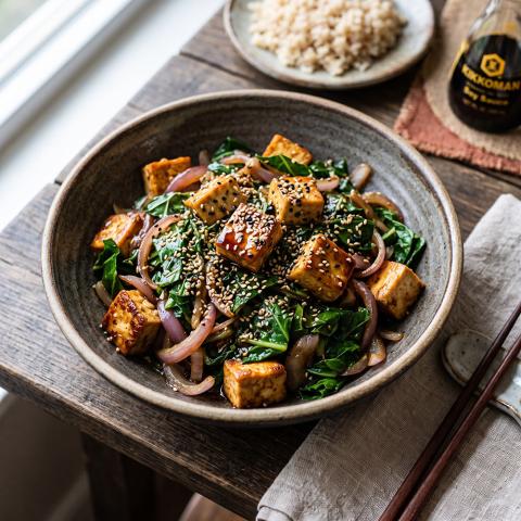 Sautéed collard greens with tofu and onions, topped with sesame seeds