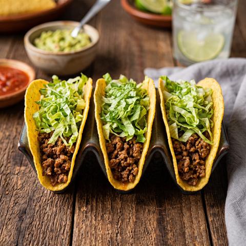 Tacos rellenos de carne picada sazonada y cubiertos con lechuga troceada
