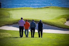 A group of four golfers walking on a golf course