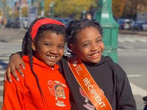 two kids posing, one is wearing a NKF Kidney Recipient sash