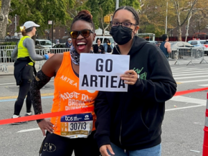 Artiea Smith mid race next to friend holding a sign of support